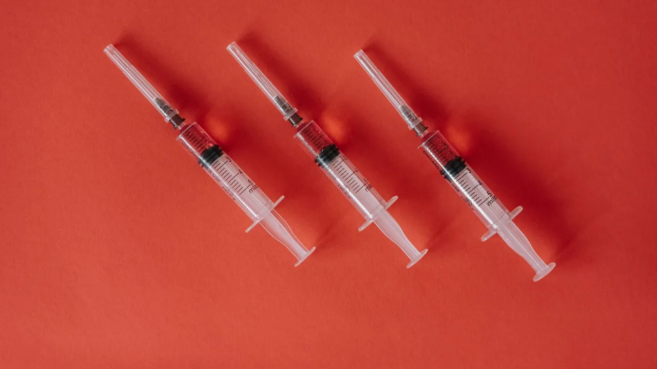 Three syringes arranged on a red surface showcasing medical equipment with copy space.