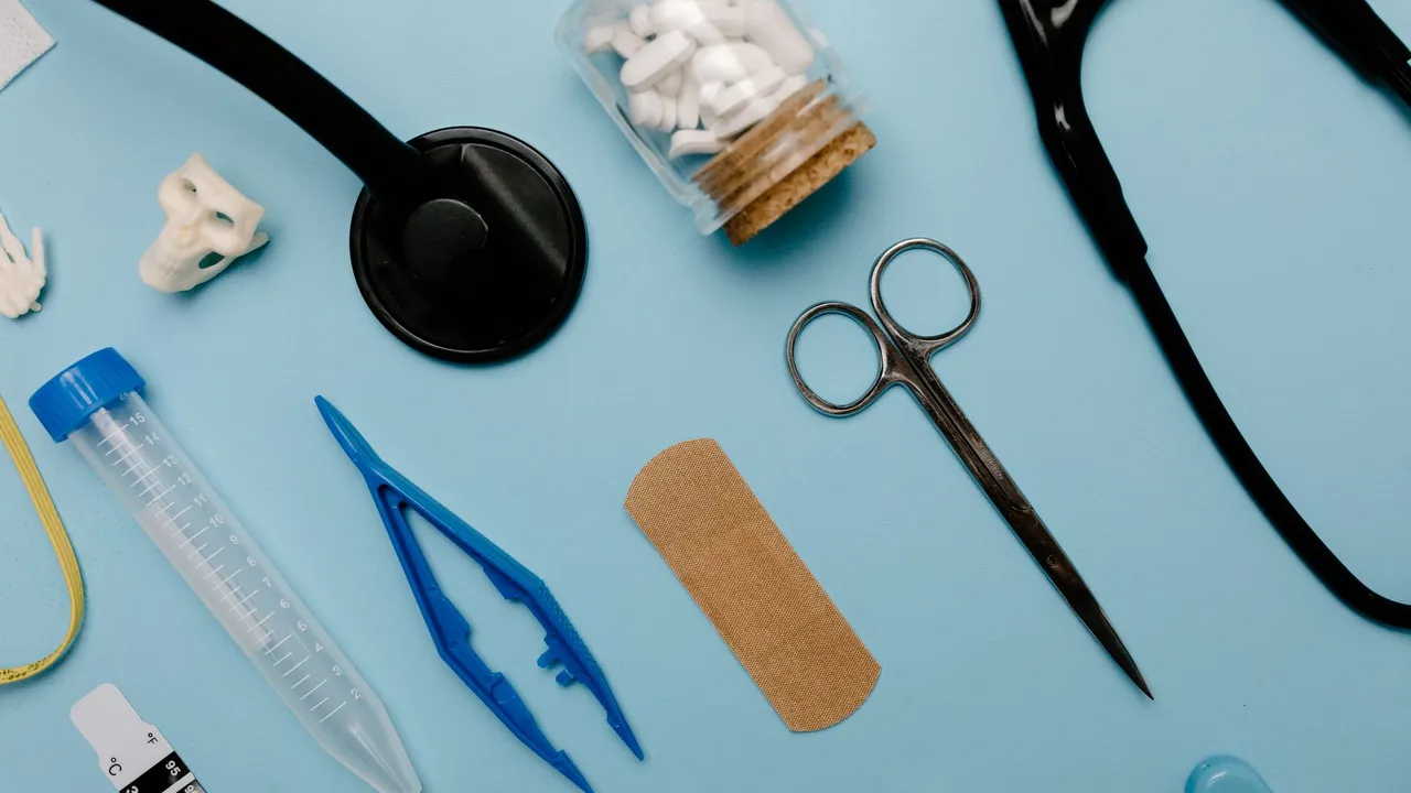 Flat lay of assorted medical tools and equipment on a blue surface.
