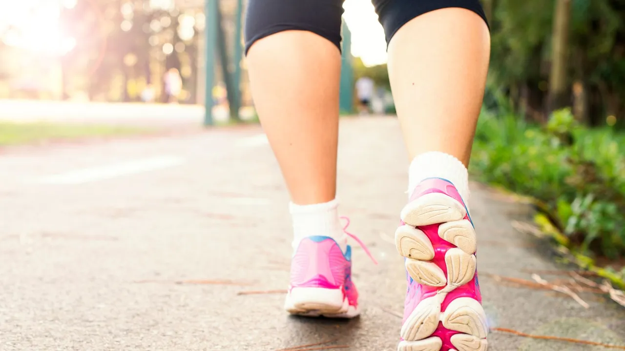 Close-up of a woman walking on a path in pink sneakers, embracing fitness and an active lifestyle.